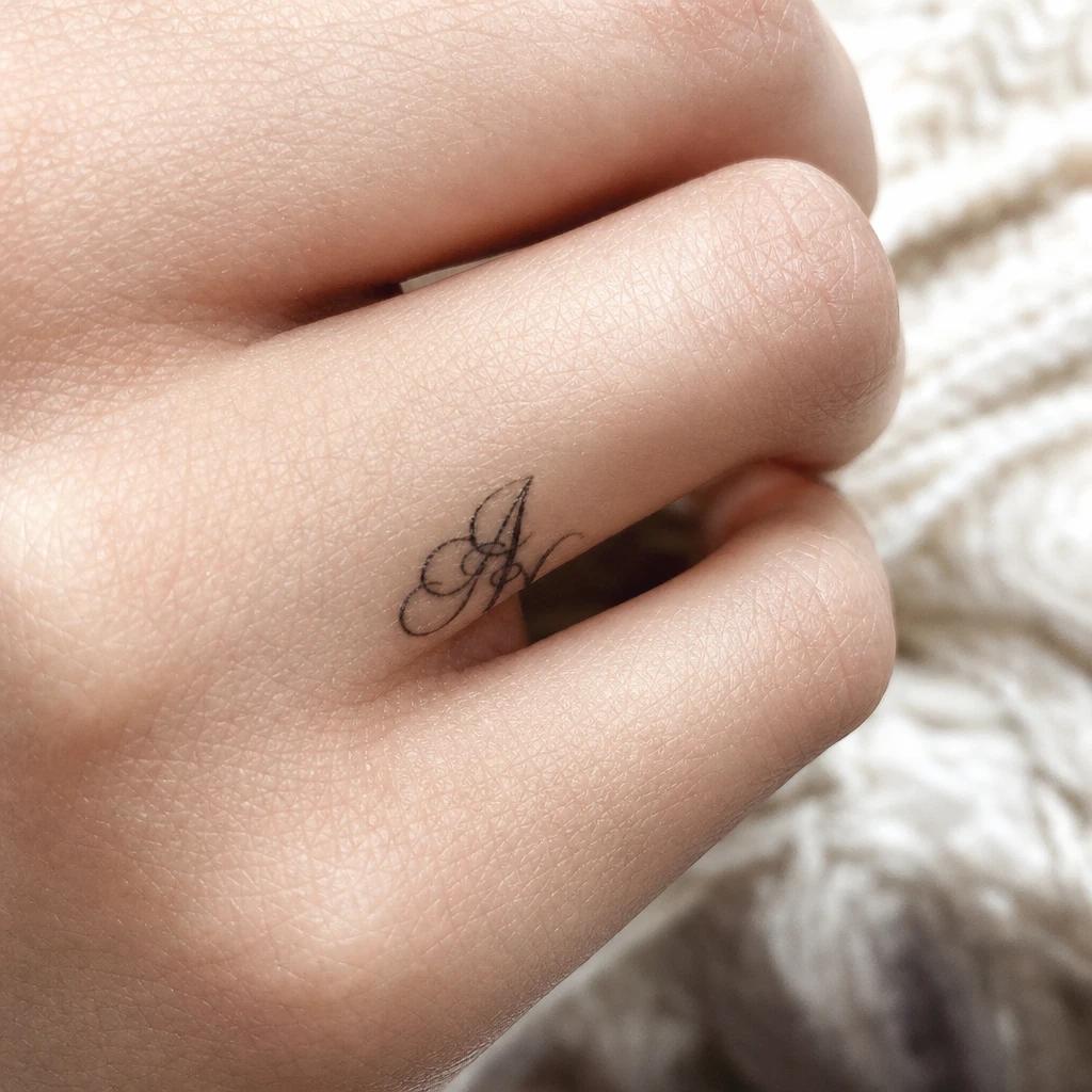 women's finger tattoo initials, realistic photo on skin